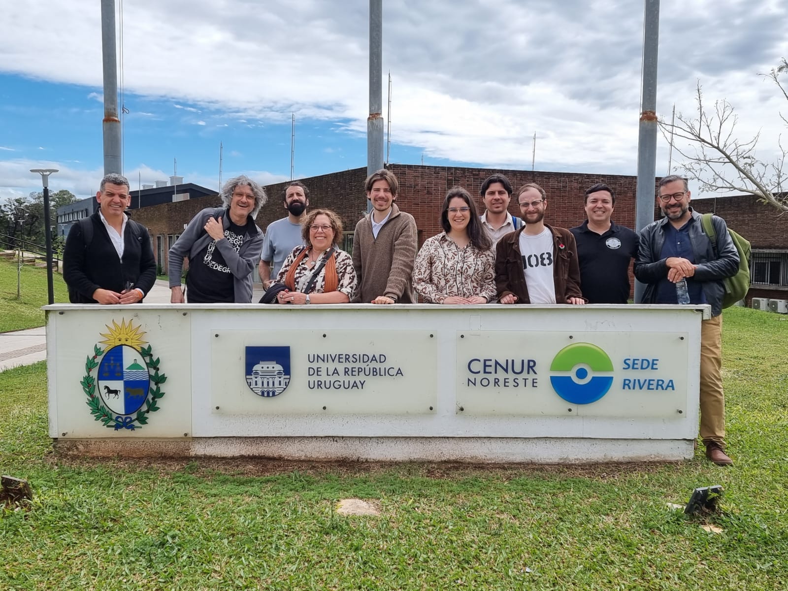 Grupo de participantes frente al cartel de la sede Rivera del Cenur Noreste